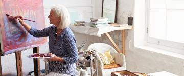 Photo of an older white woman painting in her studio